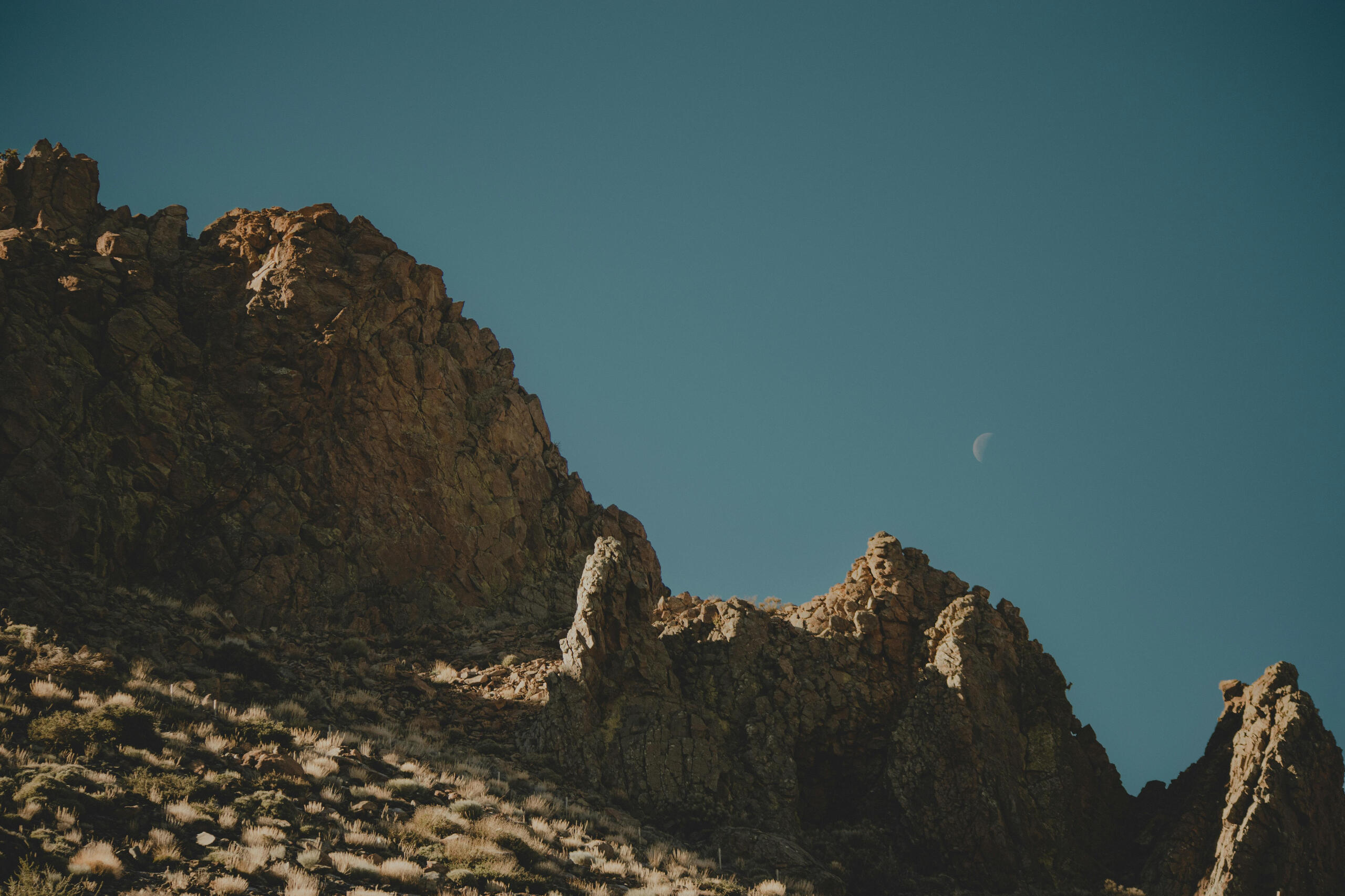Montagne désertique en journée avec la lune en fond